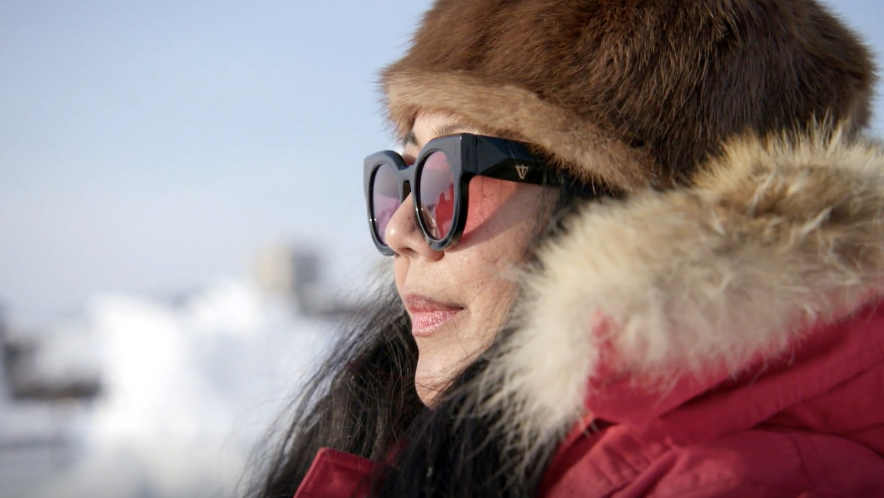 A traveller in a fur-lined hood and sunglasses in a winter landscape