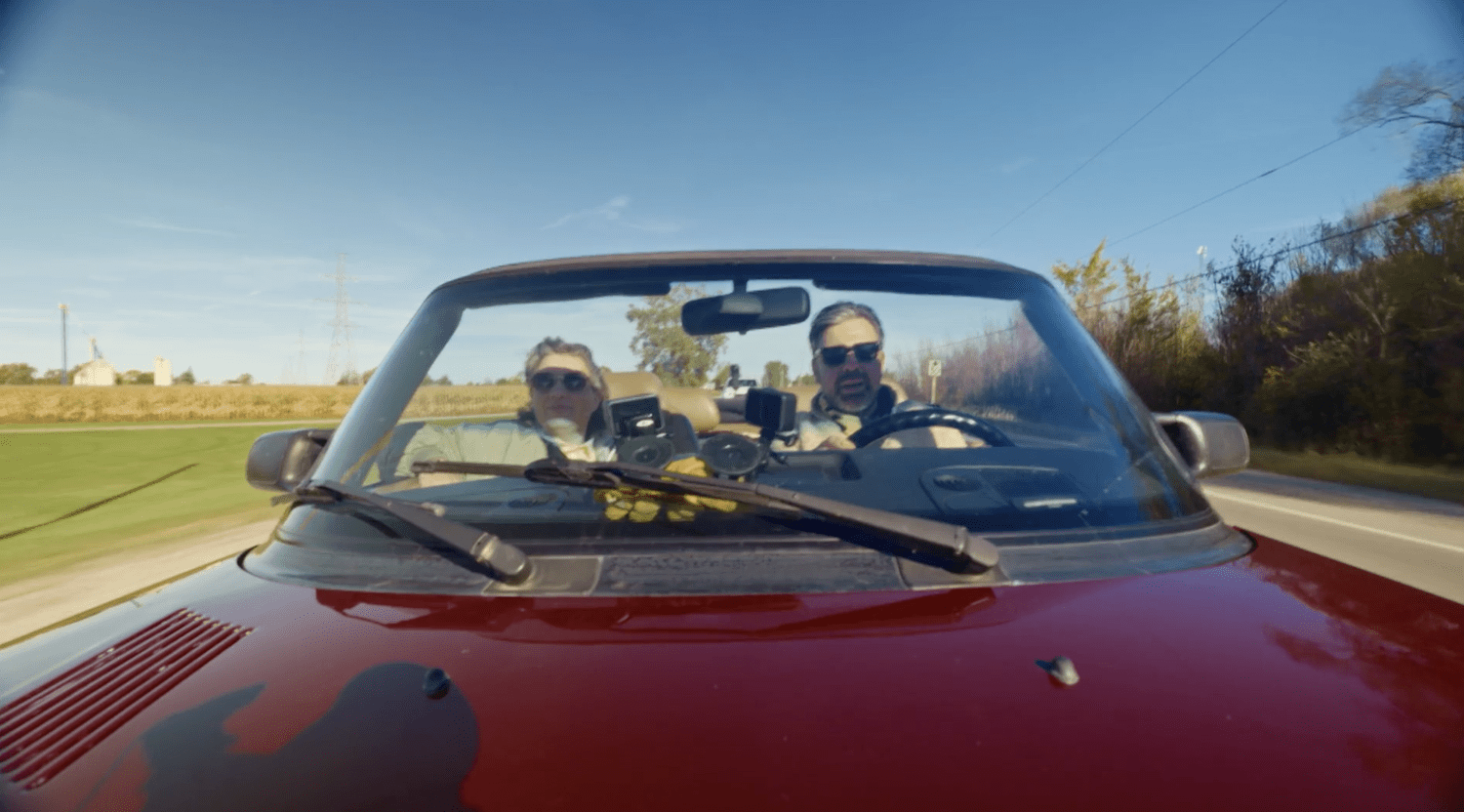 Two travellers enjoying a drive in a red convertible