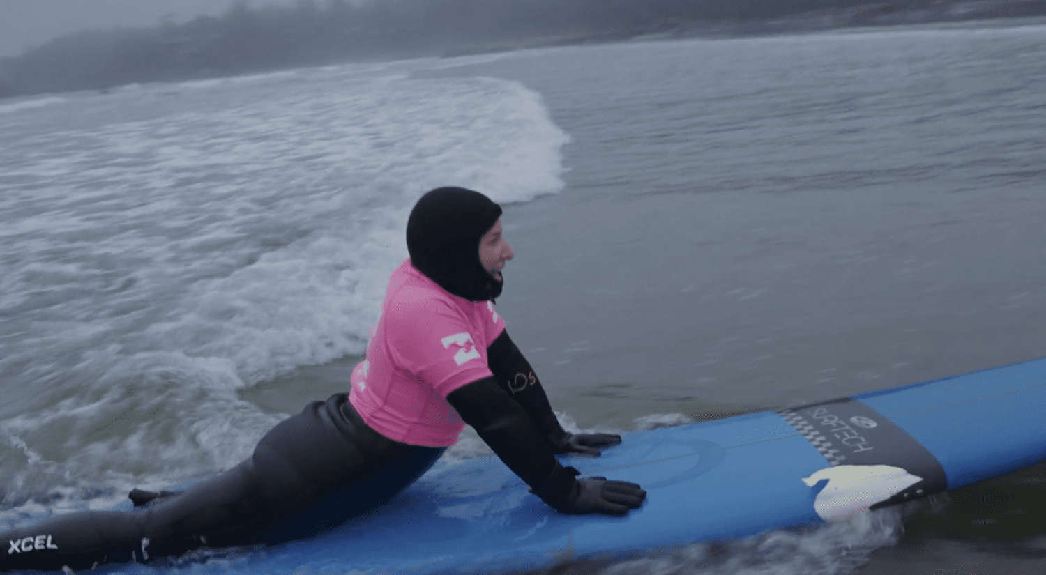 An adaptive surfer riding a wave on a blue surfboard